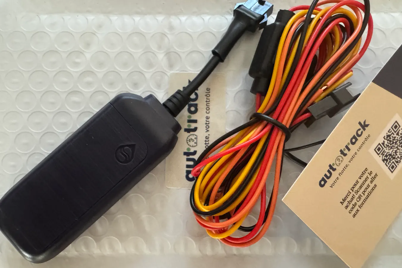 Le traceur filaire AutoTrack, son harnais 12V et sa carte de bienvenue dans leur emballage